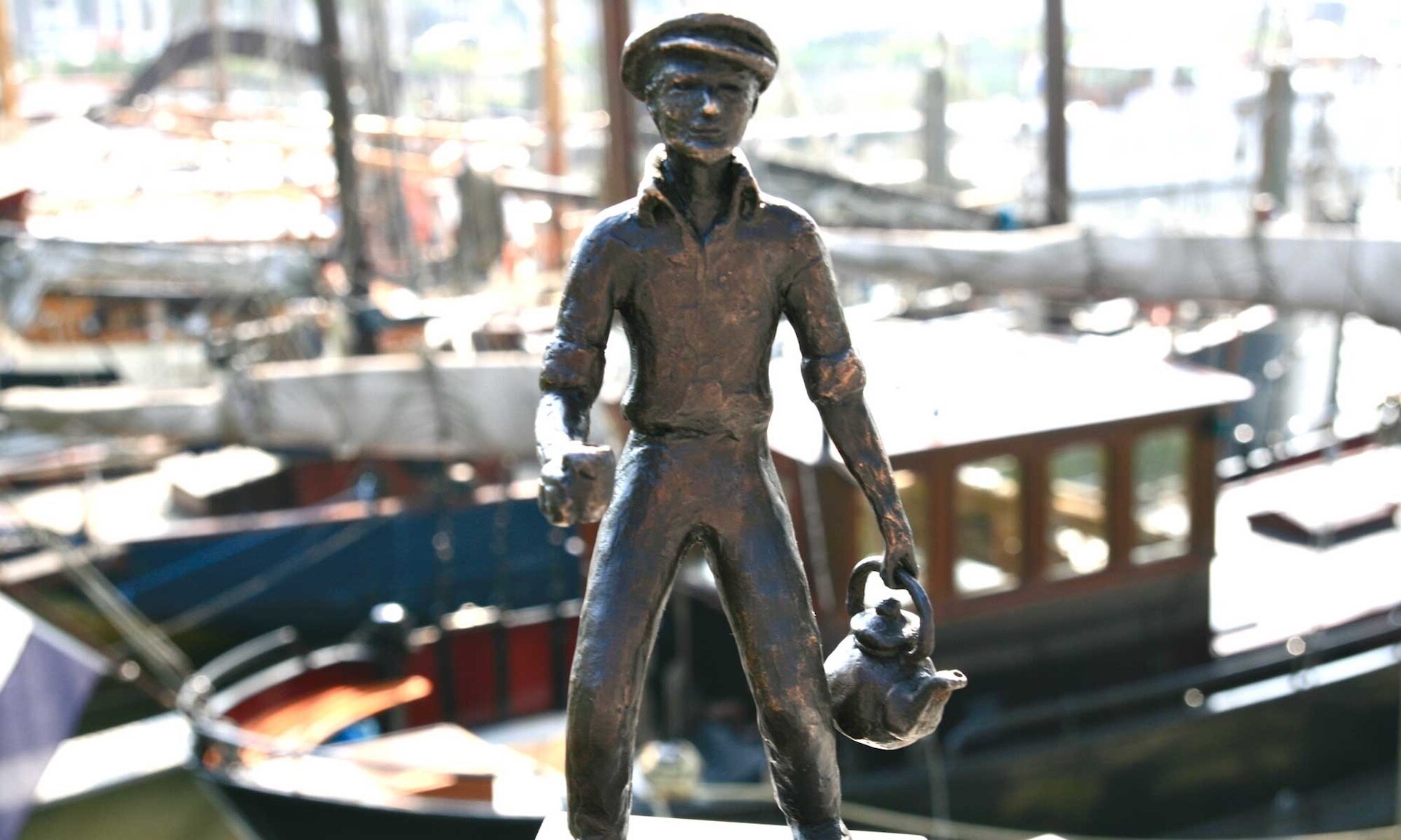 hero-beeldje-haven Zwart-witfoto uit 1973: Mies Bouwman bij het net onthulde beeld van Ketelbinkie, met havenkranen op de achtergrond